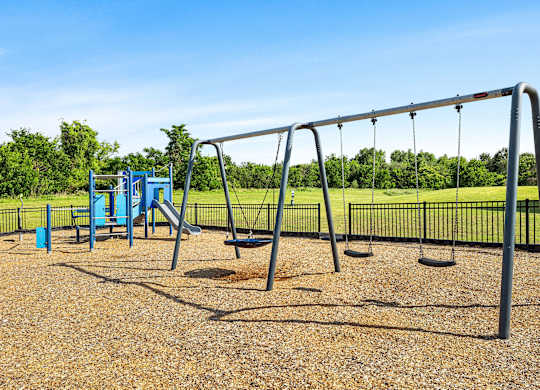 A playground with a swing set and a blue slide.