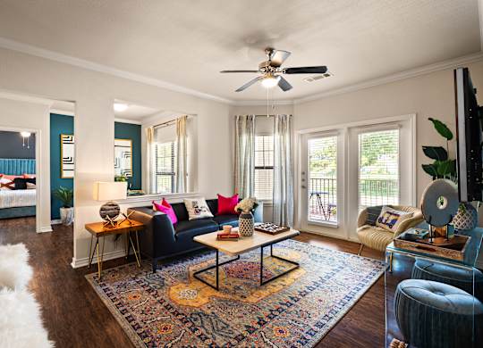 A living room with a black couch and a rug.