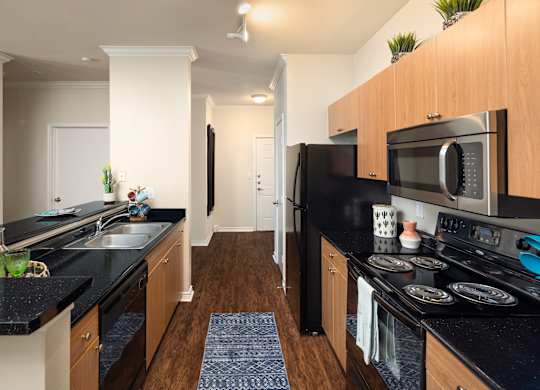 A kitchen with black countertops and wooden cabinets.