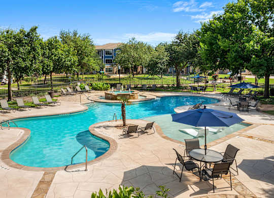 A large outdoor pool with a table and chairs.