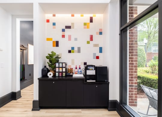 a lobby with a black bar and a coffee machine and a colorful wall with tiles