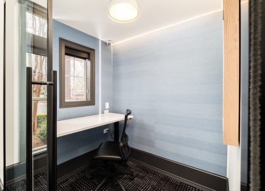 a small office area with a chair and a window