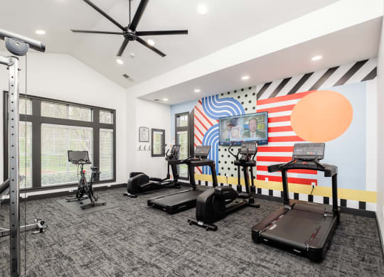 a fitness room with treadmills and weights and a large window