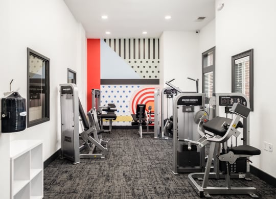 a gym with cardio machines and other exercise equipment in a room with white walls