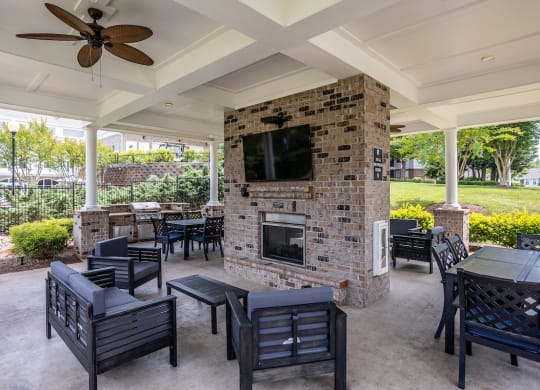 a covered patio with a fireplace and tables and chairs