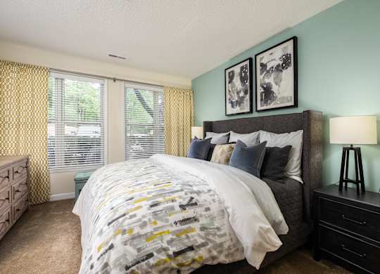 A bedroom with a bed, nightstand, and window with yellow curtains.
