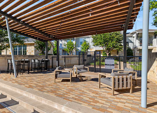 A patio with a wooden roof and furniture.