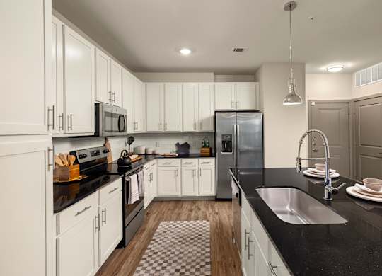 A modern kitchen with white cabinets and black countertops.