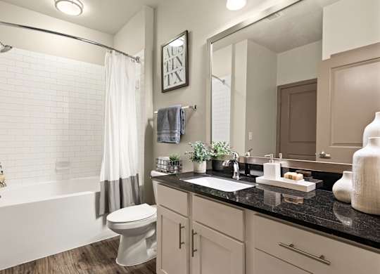 A bathroom with a white tub, sink, and toilet.