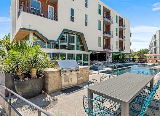 A modern apartment complex with a pool and outdoor furniture.