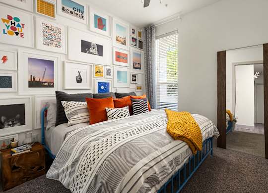 A bedroom with a bed, pillows, and pictures on the wall.