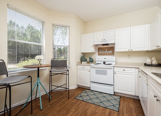 A kitchen with white cabinets and a wooden floor.
