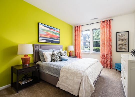 A bedroom with a bed, nightstand, and a painting on the wall.