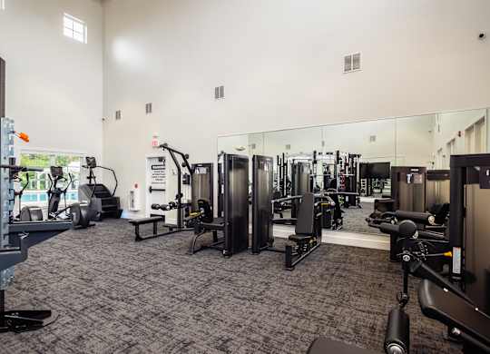 a gym with cardio equipment and mirrors on the wall