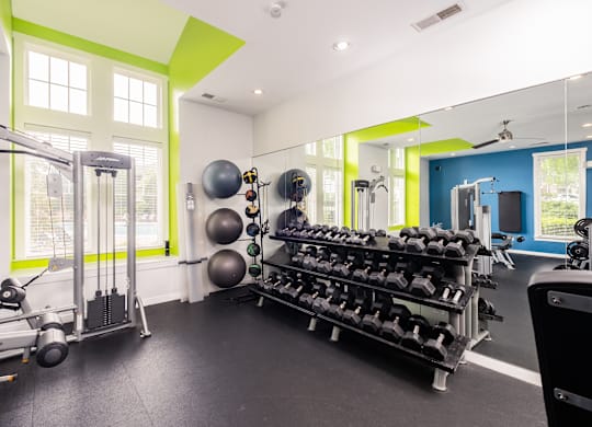 A gym with a variety of equipment including weights and exercise balls.