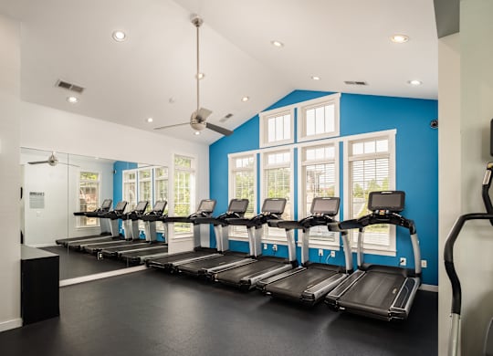 A gym with treadmills and a fan.