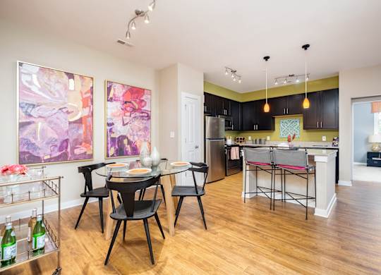 A kitchen with a dining table and chairs in the middle of the room.