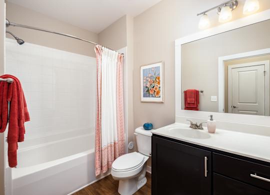 A bathroom with a white toilet, a white sink, a red towel, and a mirror.