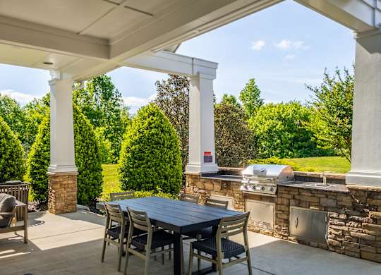 A patio with a table and chairs under a white pergola.