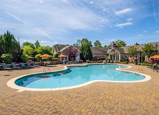 A large outdoor swimming pool surrounded by a brick patio.
