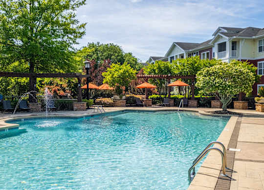 A large swimming pool surrounded by trees and a fountain.