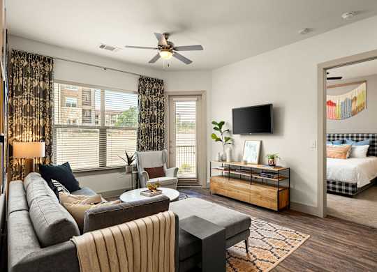 A living room with a grey couch and a television on the wall.
