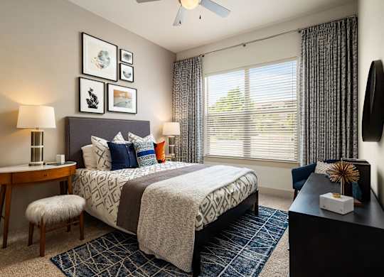 A bedroom with a bed, nightstand, and a window with blinds.