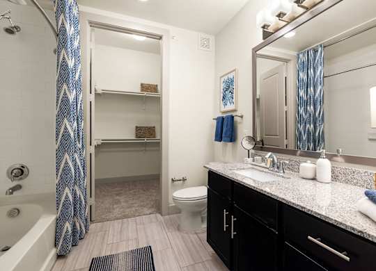 A bathroom with a white toilet, sink, and a shower with a blue shower curtain.