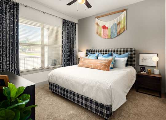 A bedroom with a bed, nightstand, and window.