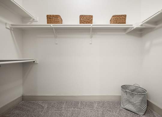A white closet with three baskets on the shelf and a trash bag on the floor.