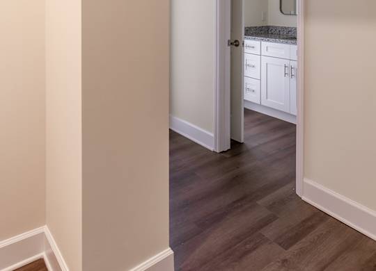 a view of a hallway with a door to a bathroom and a sink