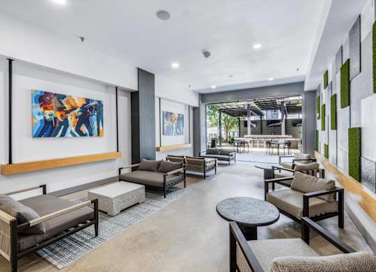 A modern living room with a large painting on the wall and a green plant on the side.