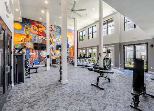 A gym with a variety of equipment including weights and a bench.