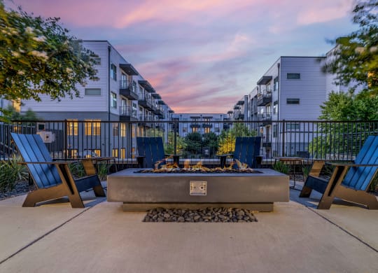 an outdoor patio with a fire pit and chairs at dusk