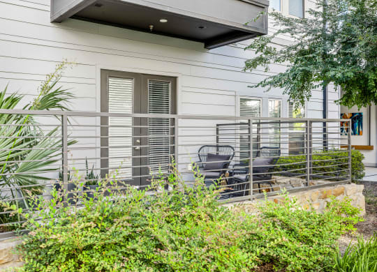 a patio with chairs and a fence in front of a house