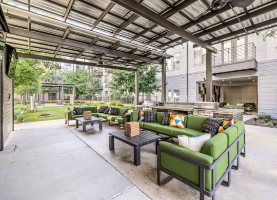a patio with green couches and tables and a building in the background