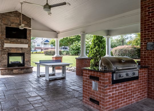 a covered patio with a fireplace and a barbecue