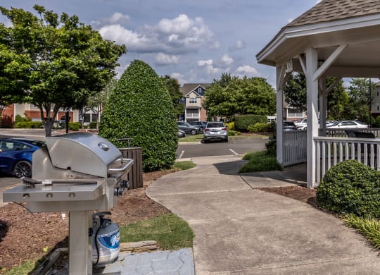 a patio with a grill and a gazebo with a parking lot in the background