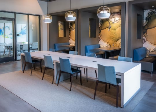 a dining room with a long white table and blue chairs