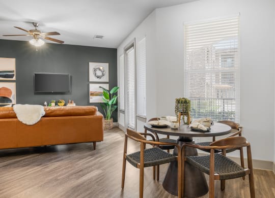 a dining area with a round table and four chairs and a couch in the background