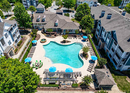 An aerial view of a swimming pool surrounded by buildings and trees.