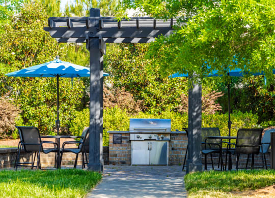 a patio with a grill and tables with umbrellas