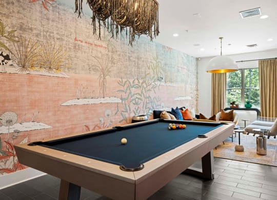 a pool table in a living room with a wall mural