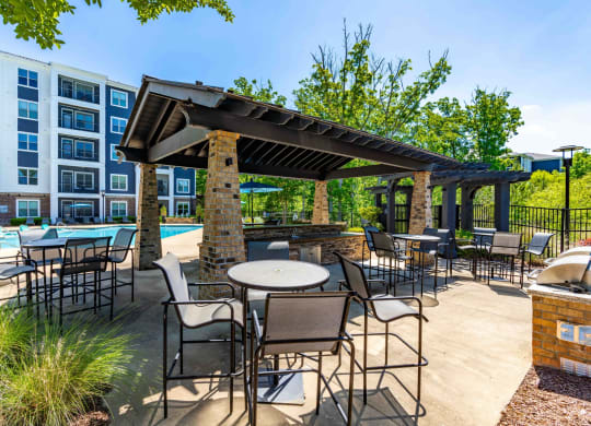 a patio with tables and chairs and a pavilion with a pool and a building
