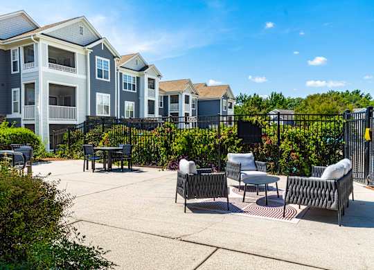 A sunny day at a residential complex with a patio and chairs.