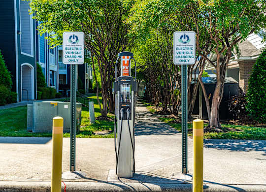 Two signs that say electric vehicle charging only stand next to a charging station.