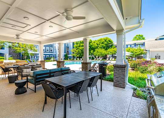 A patio with a table and chairs is covered by a roof.