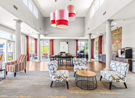 A large room with a round table and chairs with a red and white lamp hanging from the ceiling.