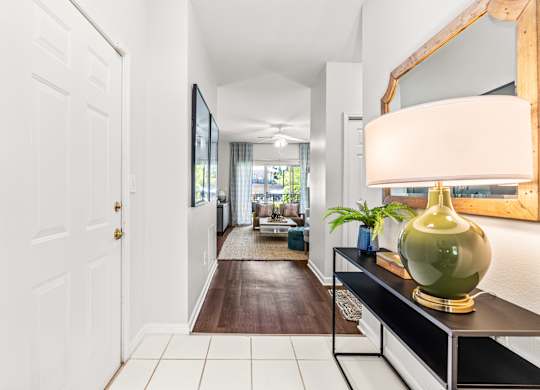 A hallway with a white door and a green vase on a black console table.