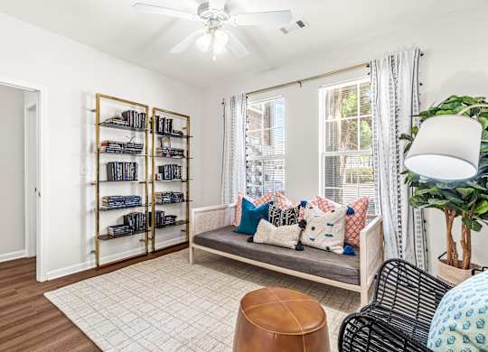 A living room with a couch, a chair, a table, a potted plant, and a bookshelf.